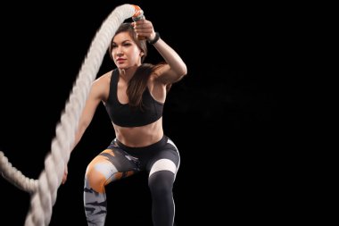 Battle ropes session. Attractive young fit and toned sportswoman working out in functional training gym doing exercise with battle ropes. Fitness and workout motivation clipart