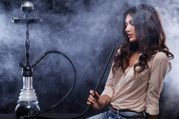 Young, beautiful woman in the night club or bar smoke a hookah or shisha. The pleasure of smoking. Sexy smoke. — Stock Photo, Image