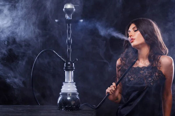 Young, beautiful woman in the night club or bar smoke a hookah or shisha. The pleasure of smoking. Sexy smoke.