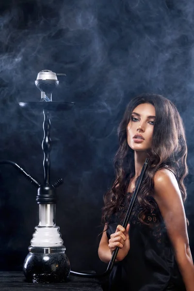 Young, beautiful woman in the night club or bar smoke a hookah or shisha. The pleasure of smoking. Sexy smoke. — Stock Photo, Image