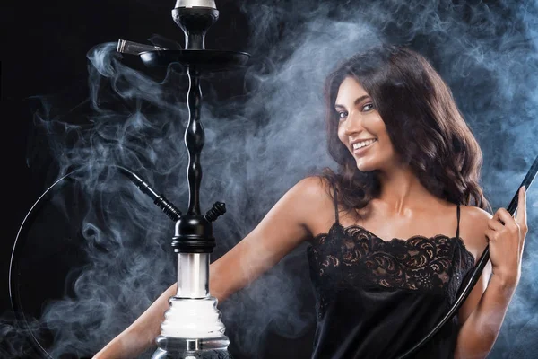 Young, beautiful woman in the night club or bar smoke a hookah or shisha. The pleasure of smoking. Sexy smoke.