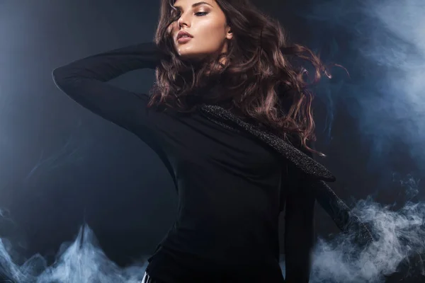 Foto de moda de uma bela jovem mulher em um vestido bonito posando sobre fundo preto com fumaça. Foto de moda com espaço de cópia — Fotografia de Stock