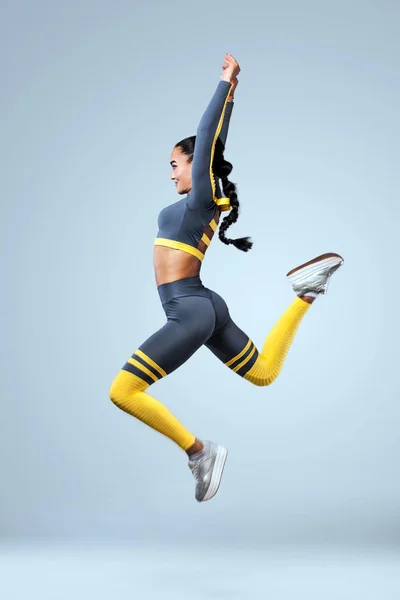 Attraente ballerina di fitness eccitata in sportwear salto di gioia isolato su sfondo grigio — Foto Stock