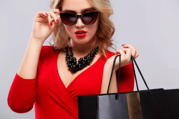 Блондинка в магазинах тримає темну сумку ізольовано на сірому фоні на чорному п'ятничному святі. Концепція продажу реклами . — стокове фото