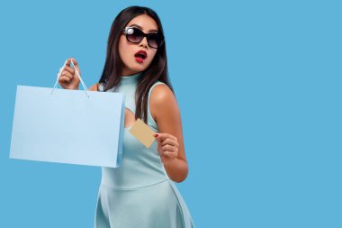 Alışveriş holding çanta ve telefon üzerinde mavi arka plan siyah Cuma tatil izole mutlu Asyalı kadın. Satılık reklamlar için kopya alanı.