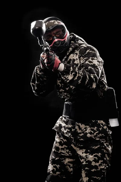 Zwaarbewapende gemaskerde soldaat geïsoleerd op zwarte achtergrond. Verf bal en laser tag sportspellen. — Stockfoto