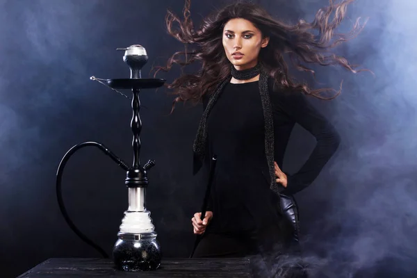 Young, beautiful woman in the night club or bar smoke a hookah or shisha. The pleasure of smoking. Sexy smoke.