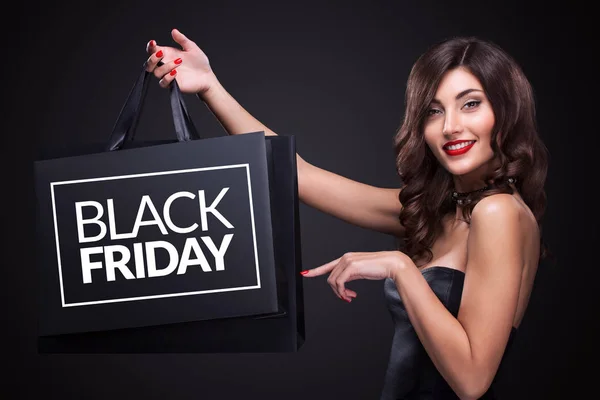 Venta. Joven mujer sonriente mostrando bolsa de compras en negro viernes de vacaciones . — Foto de Stock