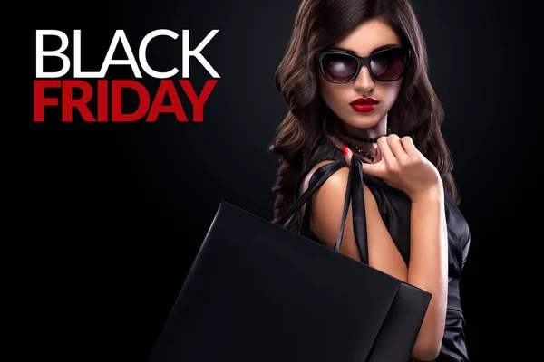 Shopping woman holding grey bag on dark background in black friday holiday — Stock Photo, Image