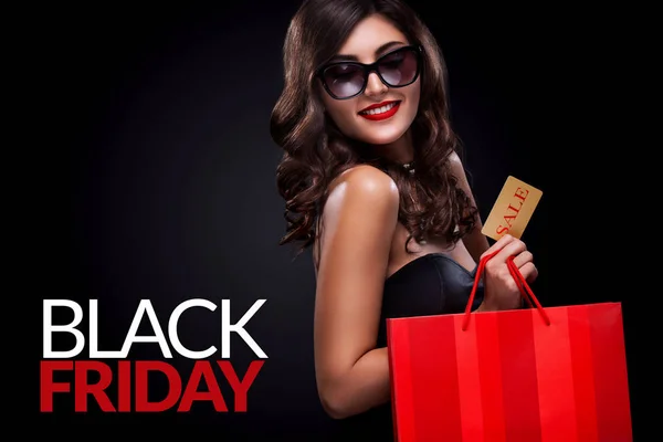 Mujer de compras sosteniendo bolsa gris sobre fondo oscuro en vacaciones de viernes negro — Foto de Stock
