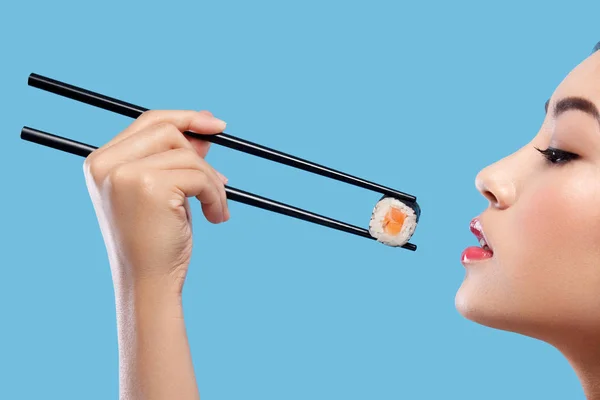 Mulher asiática com sushi comendo sushi e rola em um fundo azul. Black Friday venda de sushi . — Fotografia de Stock