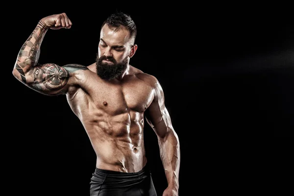 Schöner, durchtrainierter Mann, der in Jeans mit Tätowierung posiert. Sport- und Modekonzept isoliert auf schwarzem Hintergrund. — Stockfoto