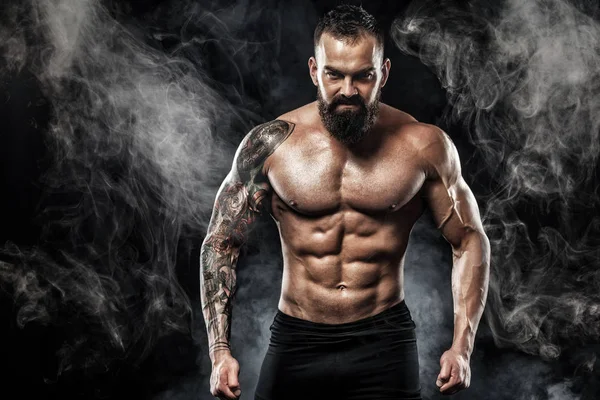 Dövme ile kot giyiyor poz uygun yakışıklı. Siyah arka plan üzerine izole spor ve moda kavramı.