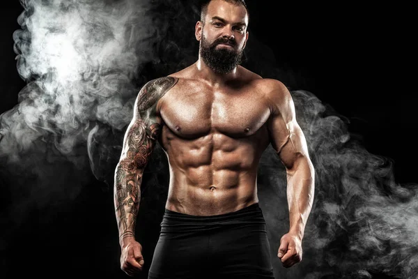 Dövme ile kot giyiyor poz uygun yakışıklı. Siyah arka plan üzerine izole spor ve moda kavramı.