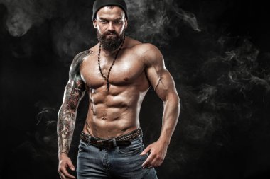 Dövme ile kot giyiyor poz uygun yakışıklı. Siyah arka plan üzerine izole spor ve moda kavramı.