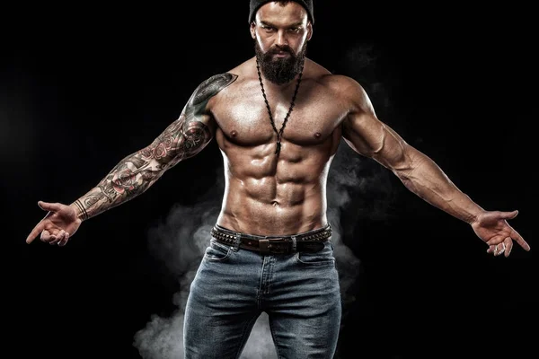 Dövme ile kot giyiyor poz uygun yakışıklı. Siyah arka plan üzerine izole spor ve moda kavramı.