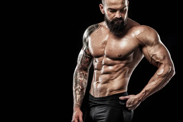 Dövme ile kot giyiyor poz uygun yakışıklı. Siyah arka plan üzerine izole spor ve moda kavramı.