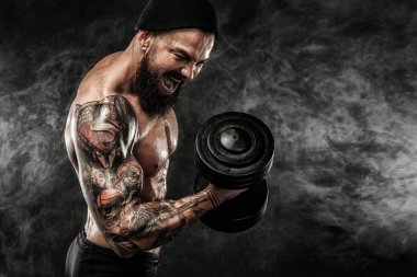 Spor salonundaki halterle spor yapan kaslı genç sporcu.
