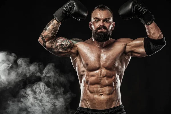 Боксер с татуировкой в боксёрских перчатках празднует чистую победу. Концепция спорта на черном фоне . — стоковое фото