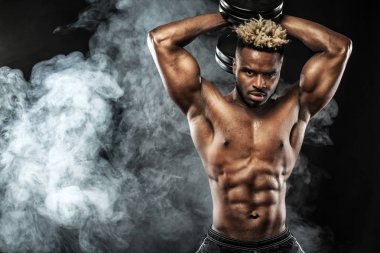 Spor salonundaki halterle spor yapan kaslı genç sporcu.