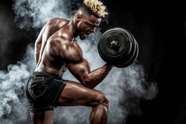 Spor salonundaki halterle spor yapan kaslı genç sporcu.