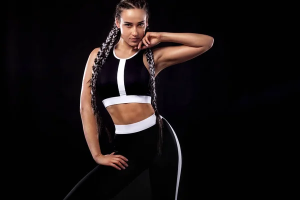 Una donna forte atletica su sfondo nero che indossa abbigliamento sportivo nero, fitness e motivazione sportiva. Concetto sportivo con spazio copia . — Foto Stock
