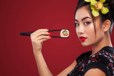 Asyalı kadın yemek suşi ve kırmızı bir arka plan üzerinde rulo. Uluslararası Kadınlar Günü, Black Friday, Setsubun Japon Festivali, suşi Satılık.