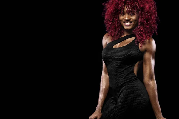 Спортивная красивая афро-американская модель, женщина в спортивной форме делает фитнес упражнения на черном фоне, чтобы оставаться в форме — стоковое фото