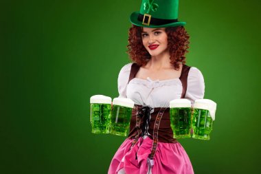 St Patricks Günü. Büyük bira bardağı yeşil arka plan üzerinde kopya alanı ile hizmet veren bir geleneksel Bavyera elbise giyen genç seksi Oktober fest garson,