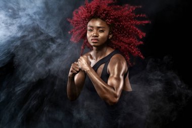 Sportif güzel Afro-Amerikan modeli, eşofman kadında fit kalmak için siyah arka plan egzersiz fitness yapar