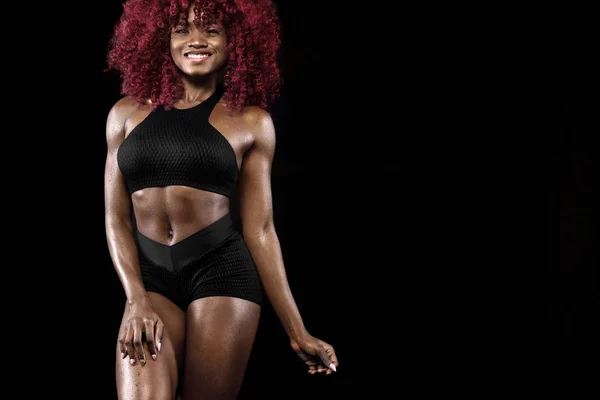 Sportig vackra afro-american modell, kvinna i sportskläder gör fitness träningen på svart bakgrund att hålla formen — Stockfoto