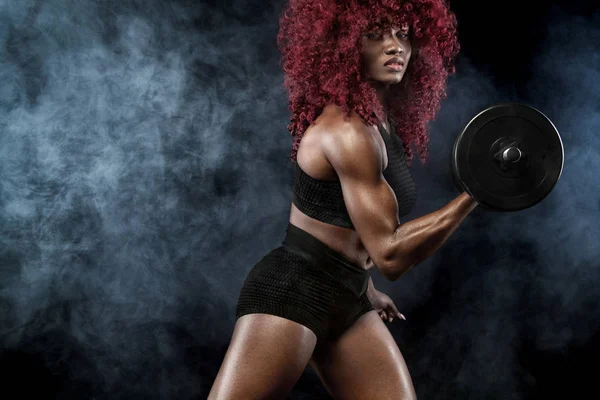 Sporty bella donna con manubri rende fitness esercizio su sfondo nero per rimanere in forma — Foto Stock