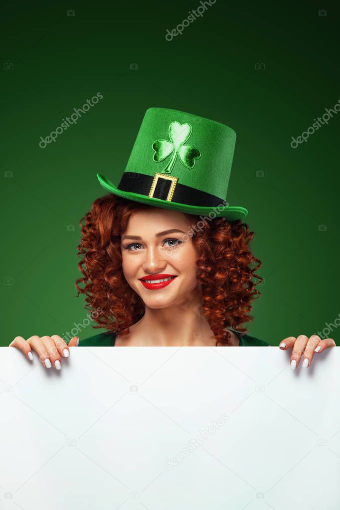 Saint Patricks Day. Young sexy Oktoberfest leprechaun, wearing a traditional Bavarian dress and hat with clover, serving big beer mugs on green background with banner for copy space