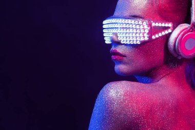 Glitter ve onun yüz ve vücut üzerinde parıldıyor ile beautyful kız. Neon güneş gözlüğü ve kulaklık ile seksi Tdj portresi