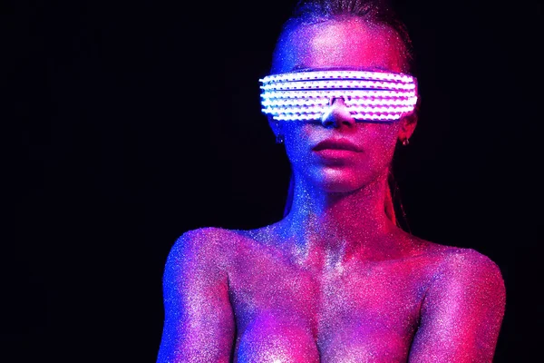 Beautyful meisje met glitter en schittert op haar gezicht en lichaam. Portret van sexy Tdj met hoofdtelefoons en neon zonnebril — Stockfoto