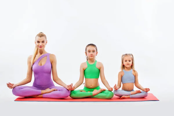 Hatha yoga fitness. Madre joven Instructor e hijas ejercen gimnasia juntos. Aislado sobre fondo blanco. Aspecto familiar . — Foto de Stock
