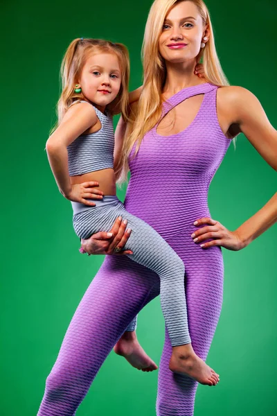 哈他瑜伽健身。年轻的母亲和女儿一起在室内锻炼。家庭外观. — 图库照片