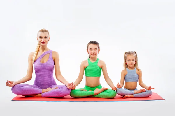 Hatha yoga fitness . Young mother Instructor and daughters exercise gymnastic together. Isolated on white background. Family look. — Stock Photo, Image