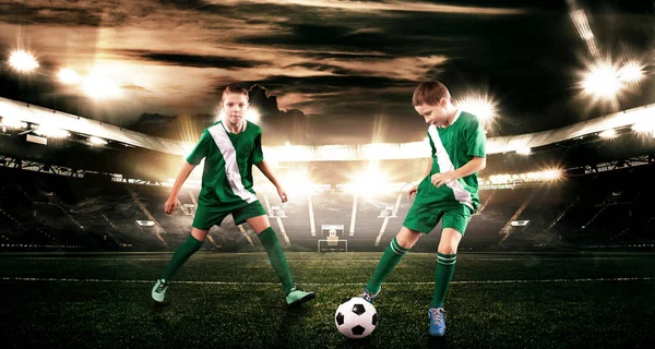 Kind - Fußballer. Junge vorwärts in Fußballsportbekleidung auf Stadion mit Ball. Sportkonzept. — Stockfoto