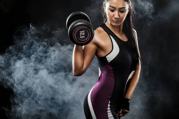 Deportiva hermosa mujer con mancuernas hace ejercicio de fitness en el fondo negro para mantenerse en forma — Foto de Stock