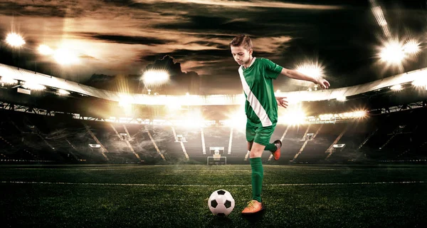 Kid - fotbollspelare. Pojke framåt i fotboll sportkläder på stadion med bollen. Sport-konceptet. — Stockfoto