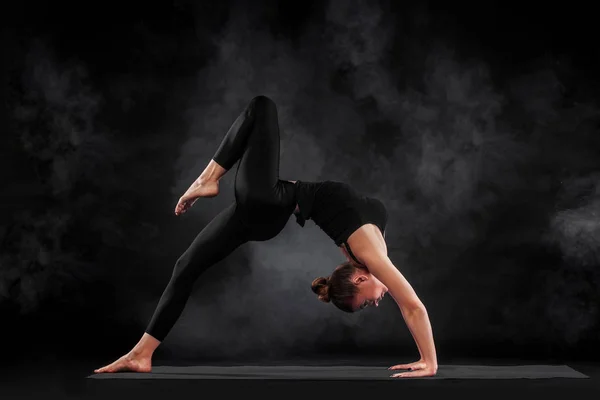 Acroyoga. Mujer joven practicando acro yoga en estera en estudio. Hatha yoga . —  Fotos de Stock