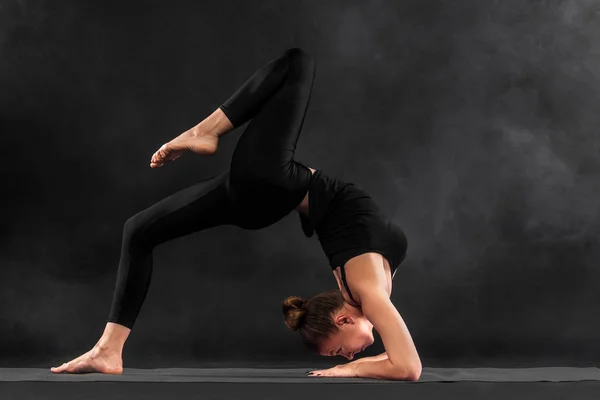 Acroyoga. Mujer joven practicando acro yoga en estera en estudio. Hatha yoga . — Foto de Stock