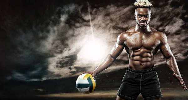 Retrato de desportista afro-americano, jogador de voleibol de praia com uma bola sobre o pôr-do-sol. Ajuste jovem em sportswear segurando bola . — Fotografia de Stock