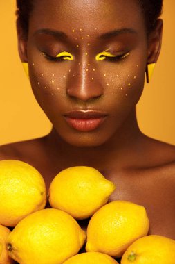 Sarı makyaj gözleri ile neşeli genç Afrikalı kadın. Kadın modeli ile sarı limon sarı arka plana karşı.