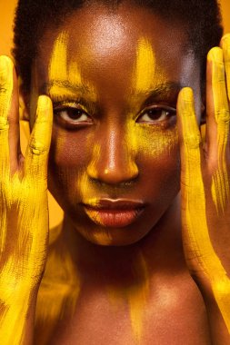 Sarı bahar makyaj gözleri ile neşeli genç Afrikalı kadın. Kadın modeli sarı yaz arka planı gülüyor.