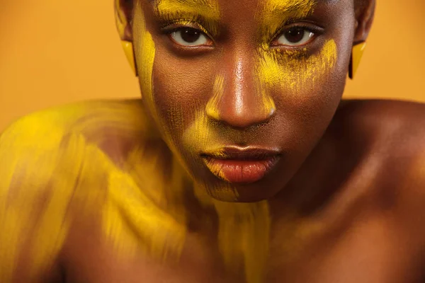 Vrolijke jonge Afrikaanse vrouw met gele voorjaar make-up op haar ogen. Vrouwelijke model lachen tegen geel zomer achtergrond. — Stockfoto