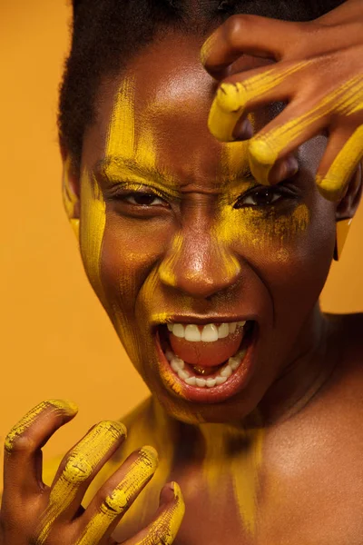 Vrolijke jonge Afrikaanse vrouw met gele voorjaar make-up op haar ogen. Vrouwelijke model lachen tegen geel zomer achtergrond. — Stockfoto