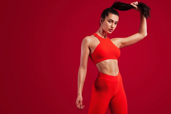 Una fuerte atlética, mujer bailarina, posando sobre fondo rojo vistiendo en la ropa deportiva, fitness y motivación deportiva con espacio para copiar . — Foto de Stock