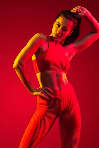 Egy erős, sportos, nő táncos, pózol, piros háttér visel a sportruházat, fitness és sport motiváció a másol hely. — Stock Fotó